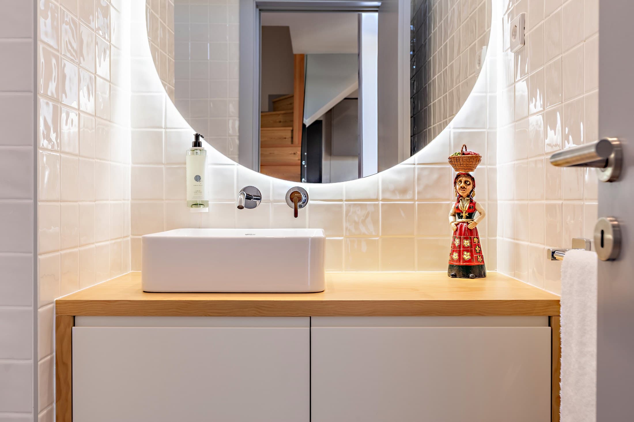 Lavatório e espelho redondo de uma casa de banho do Almada 505.