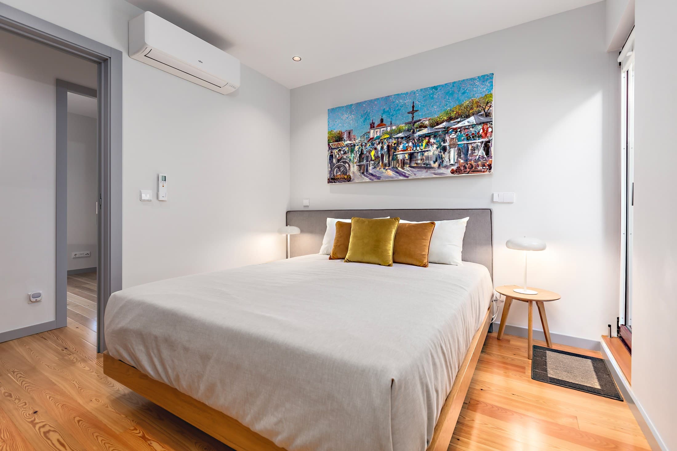 Quarto do Almada 505 com cama de casal e quadro colorido.