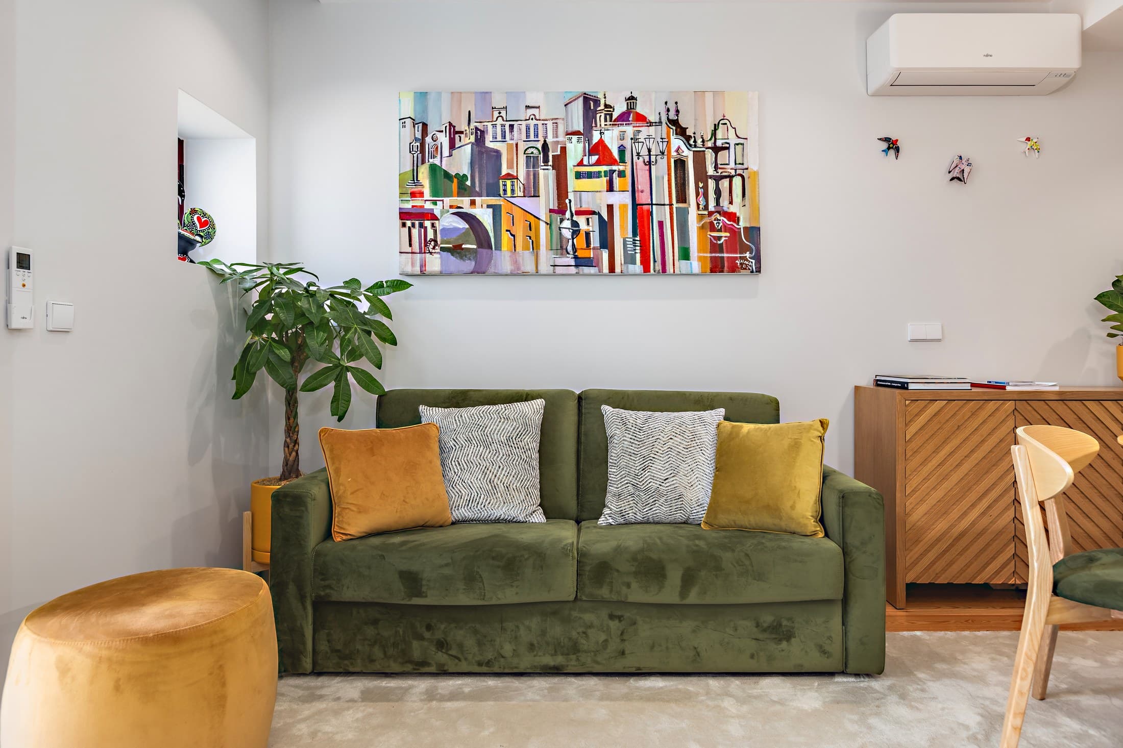 Sala do Almada 505 com sofá verde e ambiente acolhedor.